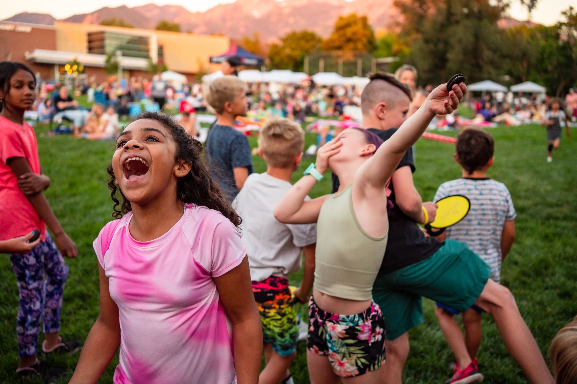 Picture of several children smiling and laughing while playing in a park.